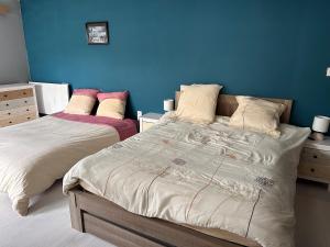 a bedroom with two beds and a blue wall at Chambre pour 4 personnes avec SdB privative et jacuzzi in Le Petit-Couronne