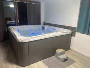a large jacuzzi tub in a room with a stool at Chambre pour 4 personnes avec SdB privative et jacuzzi in Le Petit-Couronne