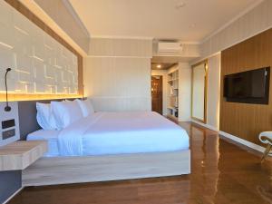 a bedroom with a white bed and a flat screen tv at Sira Boutique Chiang Mai in Chiang Mai
