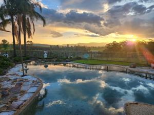 a pool in a yard with a sunset in the background at Blueberry Hill Vineyard Stay in Rothbury