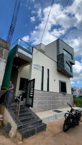 a man standing outside of a building with a motorcycle parked outside at Private room in a residential area in Hospet