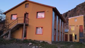 ein orangefarbenes Haus mit einer Treppe vor einem Berg in der Unterkunft Los Milenarios in El Chalten