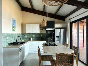 a kitchen with white cabinets and a table with chairs at Villa Petite Anse in Petite Île