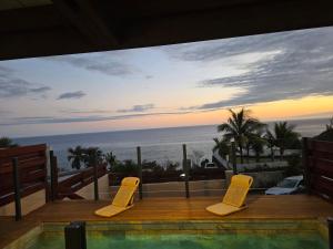 a view of the ocean from a patio with yellow chairs at Villa Petite Anse in Petite Île