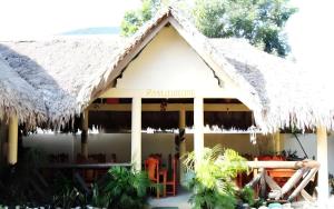 a building with a straw roof and a restaurant at Palm Grove Saud Holiday Complex Hotel in Laoag