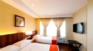 a hotel room with two beds and a television at V Hotel and Apartel in Baguio