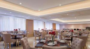 a restaurant with tables and chairs and red flowers at Guangna Hotel in Huizhou