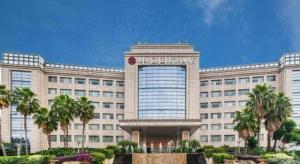 a large building with palm trees in front of it at Centenio International Hotel in Foshan