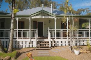 Weyba DownsにあるStunning Modern Queenslander, steps to Lakeの白い柵のある家とその前に犬がいる
