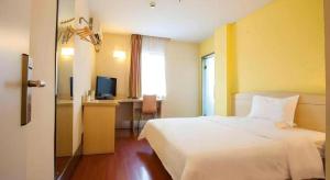 Un dormitorio con una cama y un escritorio con televisión. en 7 Days Inn Shaoguan Lechang, en Lechang