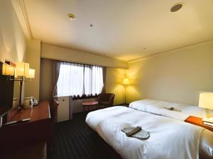 a hotel room with two beds and a desk at Hotel Royal Hill Fukuchiyama and Spa in Fukuchiyama