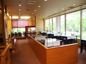 a restaurant with white tables and chairs and windows at Hotel Royal Hill Fukuchiyama and Spa in Fukuchiyama