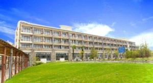 a large building with a green field in front of it at Huangshan Scholars Conference Hotel in Huangshan
