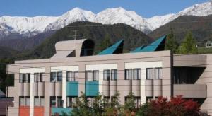白馬村にあるOkanoue Hotel Miyagawaの雪山を背景にした建物