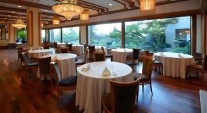un restaurant avec des tables et des chaises blanches et de grandes fenêtres dans l'établissement Hotel Grand Shinonome, à Tsukuba 100 autres photos