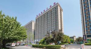 a large building with a sign on top of it at Jinjiang Select Luoyang Longmen Guanlin Train Station Branch in Luoyang