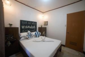 パングラオにあるD' Barn Hostel Panglaoのベッドルーム1室(白いベッド1台、壁に看板付)