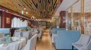 une salle à manger avec des tables blanches et des chaises bleues dans l'établissement Bati Holiday Hotel, à Zhongshan