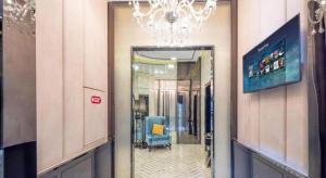 a hallway with a blue chair and a chandelier at Xana Hotelle Wuhan Lingjiao Lake Wanda Plaza Branch in Wuhan
