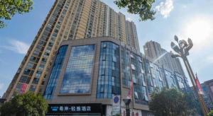 a large building with glass windows in a city at Xana Lite Anqing Yuexi Swan Squre Branch in Yuexi