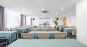 a conference room with tables and chairs and a screen at Xana Hotelle·Yutian in Tangshan