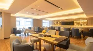 a restaurant with tables and chairs in a room at Echarm Hotel Aegean Shopping Park Zhonghuan Plaza in Tangshan