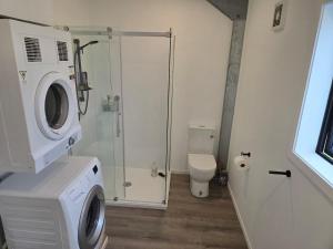 a bathroom with a washing machine and a toilet at Valley Views Near City & Coast in Tahere +14 photos