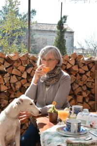 Una donna seduta a un tavolo che beve da un bicchiere con un cane di A Casa di Susi a Castelnuovo del Garda