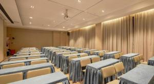 Echarm Hotel Liuzhou High-speed Railway Station في ليوشو: غرفة بها صفوف من الكراسي والستائر