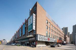 a large brick building on a city street with at Borrman Hotel Qianjiang High-speed Railway Station Lobster City in Qianjiang