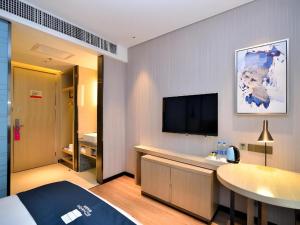 a hotel room with a bed and a flat screen tv at Echarm Hotel Xian Ming City Wall South Gate in Xi'an