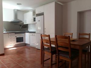 una cocina con armarios blancos y una mesa y sillas de madera. en Can Mayol, en Alaró