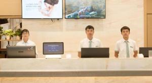 three men standing at a desk with their computers at City Comfort Inn Baise Longlin Yingbin Road in Lengshui