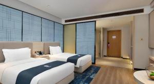 長沙市にあるEcharm Hotel Changsha Gaoqiaoのベッド2台と廊下が備わるホテルルームです。