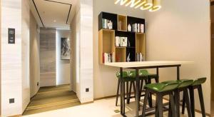 a bar with green stools and a book shelf at City Comfort Inn Liuzhou Sanjiang Gulou Bird's Nest in Sanjiang
