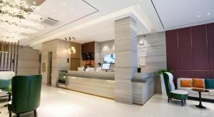 a lobby with a reception desk and green chairs at City Comfort Inn Beiliu Yongfeng Plaza Chengnan Bus Station in Yulin