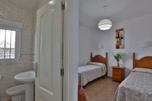 a bathroom with two beds and a sink and a mirror at Apartamentos El Madroñal in Coto Rios