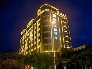 万寧市にあるCity Comfort Inn Wanning Wan'An Avenue High Speed Railway Stationの夜時計付きの高層ビル