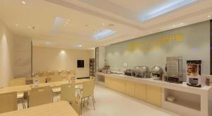 a restaurant with a cafeteria with tables and chairs at City Comfort Inn Liuzhou Wuxing Walking Street in Liuzhou