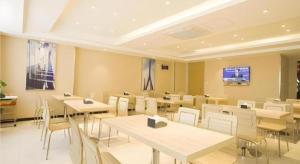a dining room with tables and white chairs at City Comfort Inn Zhanjiang South Railway Station in Zhanjiang