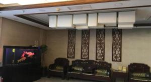 a room with a flat screen tv and three chairs at PAI Hotels Jinzhou Yi County Railway Station in Jinzhou