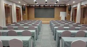 a lecture hall with tables and chairs and a screen at James Joyce Coffetel Shijiazhuang Wanda Plaza Tangu Metro Station in Shijiazhuang