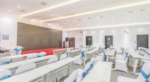 a classroom with white chairs and a large screen at Xana Hotelle Tangshan North Railway Station in Fengrun
