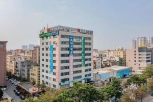 a tall white building in a city with buildings at Borrman Hotel Zhanjiang Wuchuan Jinsha Plaza in Zhanjiang