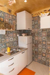 uma pequena cozinha com armários brancos e azulejos na parede em Casa Macaia em La Spezia