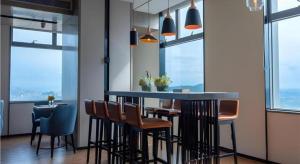 a kitchen with a bar with chairs and windows at Echarm Hotel Nanning Wuxiang Headquarters Base in Nanning