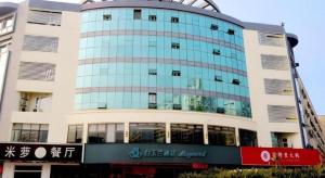 un grand bâtiment en verre avec un panneau devant lui dans l'établissement Magnotel Hotel Xuzhou Xinxin Yurun Plaza Zhongwu Road, 