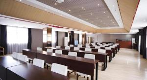 a large room with tables and white chairs at GreenTree Inn Shangrao Wuyishan Avenue Meide Yinxiang in Shangrao