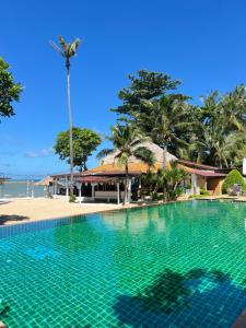a swimming pool next to a beach with a palm tree at Coco Lanta Resort in Ko Lanta