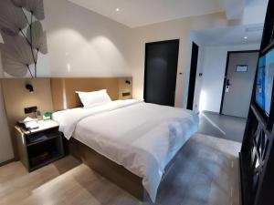a bedroom with a large white bed and a television at GreenTree Inn Express Fuzhou Linchuan District Gandong Auto City in Fuzhou +172 photos